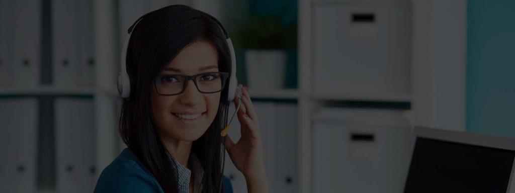 A woman with glasses and headphones on smiling.